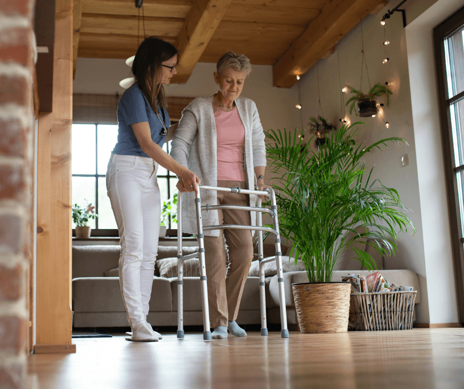A caretaker assisting an elderly woman who is using a walker.