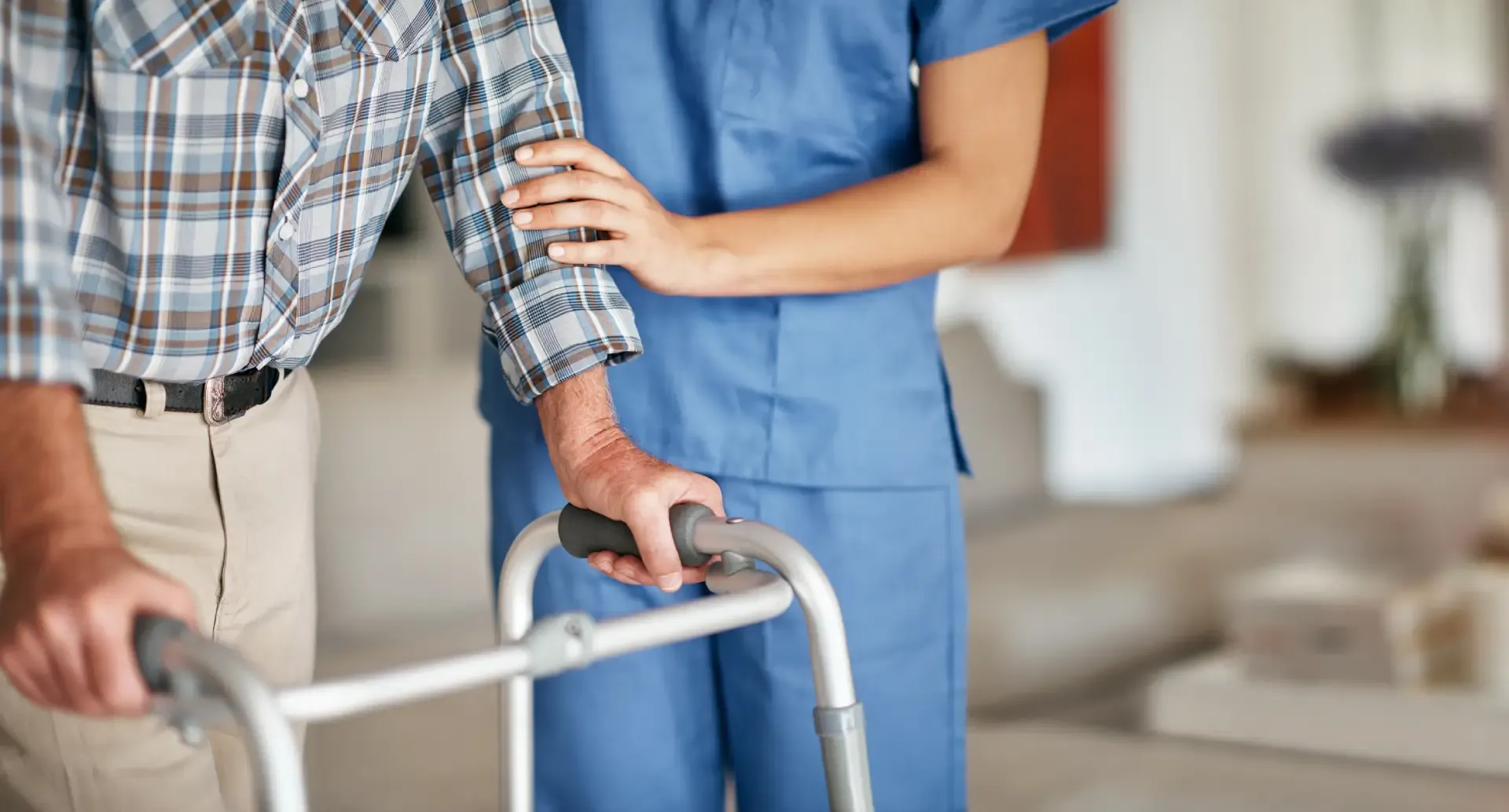 A caregiver assisting an elderly man who is using a walker.